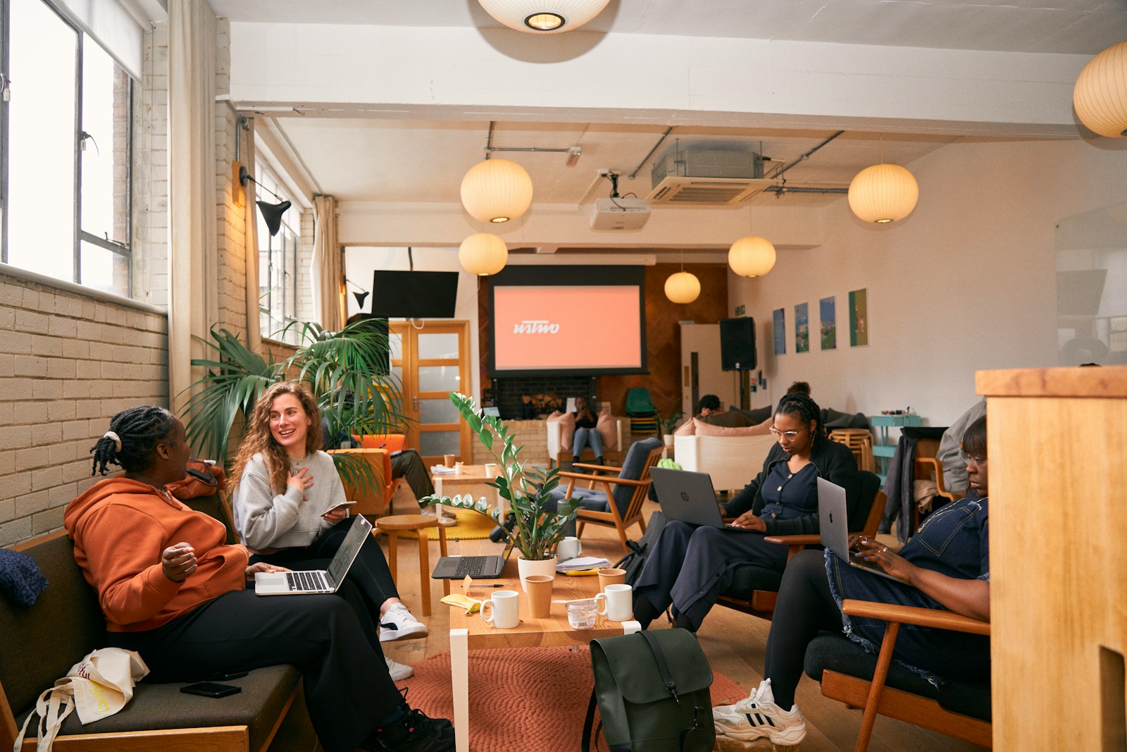 a group of people sitting in a room with laptops
