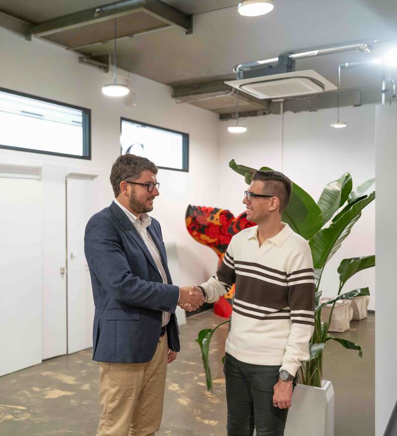 Two men shaking hands in a bright, contemporary office